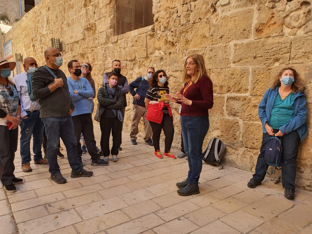 דודי אלבז מדריכה קבוצת מטיילים ליד קיר אבן עתיק